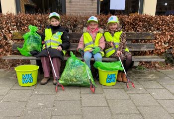 Drie vrolijke MikMakkers zitten op een bankje bij de bieb.